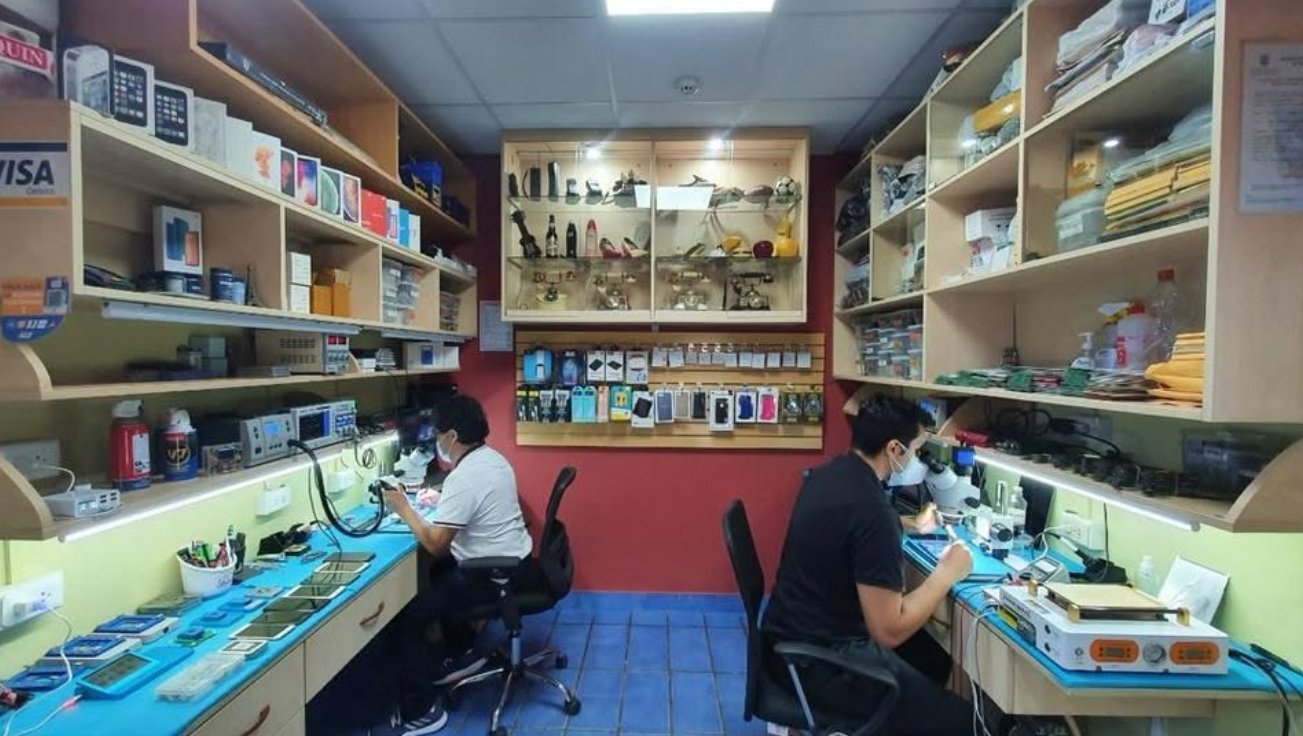 Interior del taller de Teleserv con dos técnicos trabajando en mesas con microscopios y estaciones de soldadura